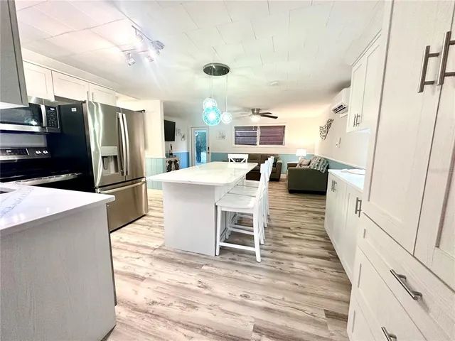 a kitchen with stainless steel appliances a refrigerator a stove a sink dishwasher and white cabinets with wooden floor