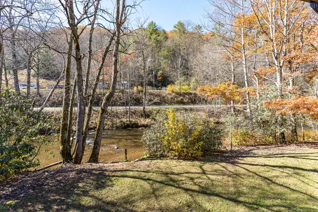 a view of a house with a small yard and large tree