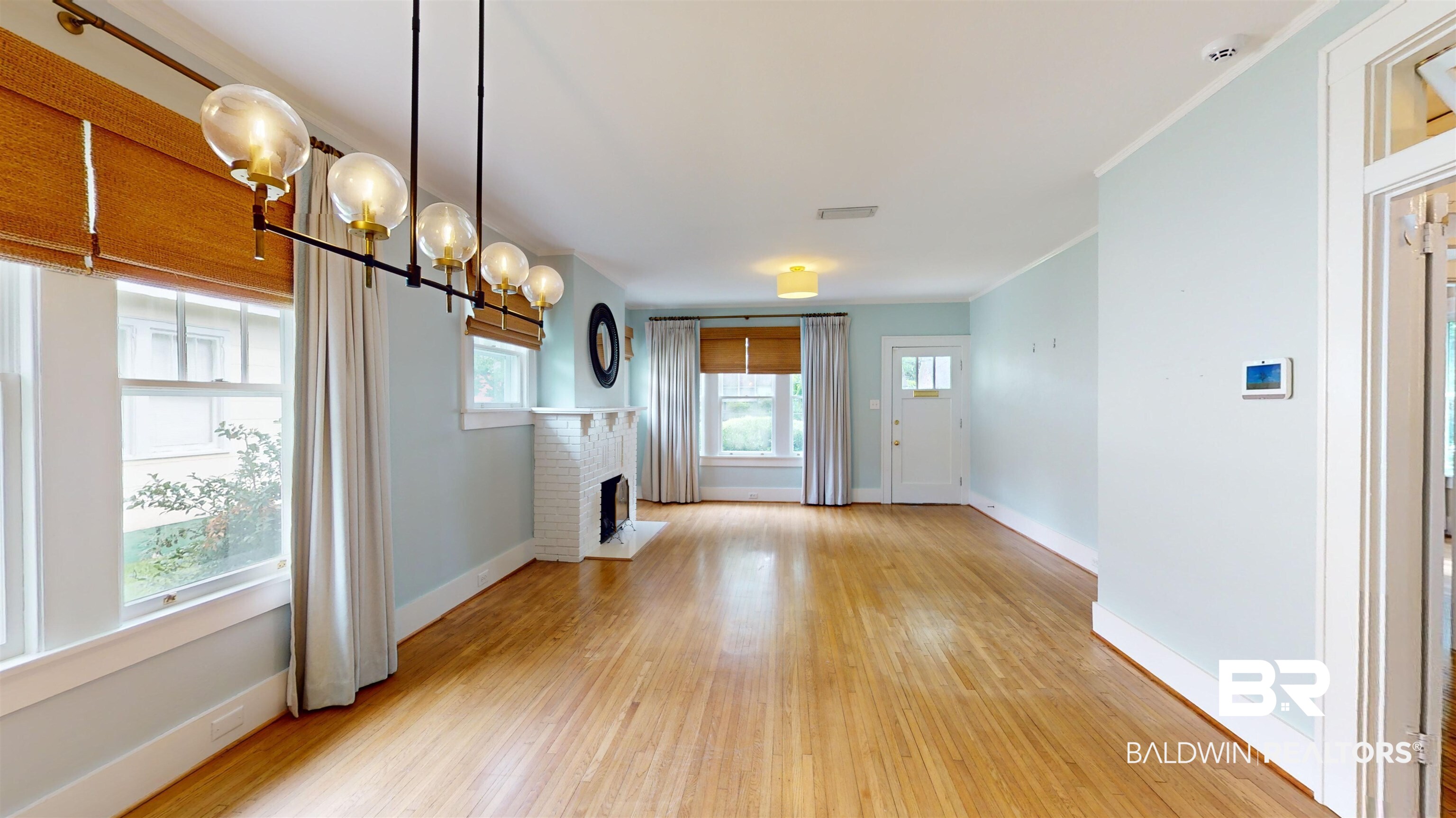 4307 Stein Street Mobile, AL 36608 - Photo 5 of 28 Unfurnished living room featuring a brick fireplace, crown molding, light wood-type flooring, and a chandelier