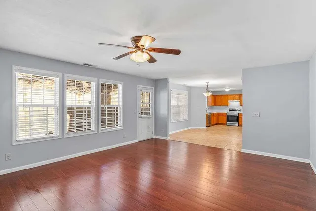 a view of an empty room with a window and wooden floor