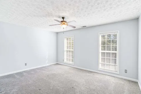 an empty room with windows and fan