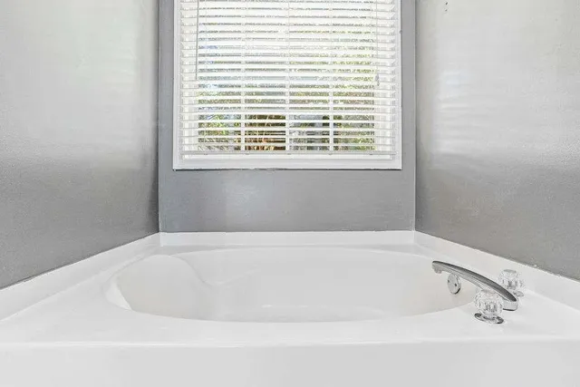 a white bath tub sitting in a bathroom next to a window