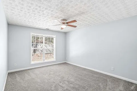 an empty room with windows and fan