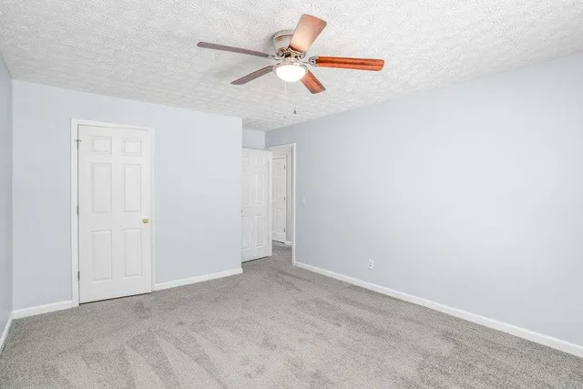 an empty room with ceiling fan and window