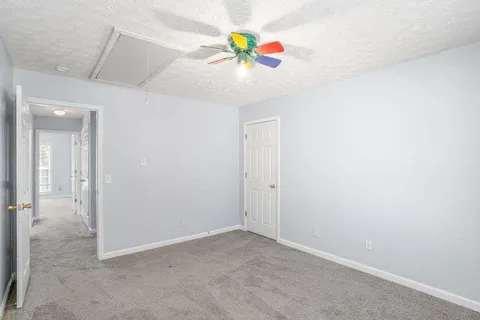 an empty room with fan and hallway