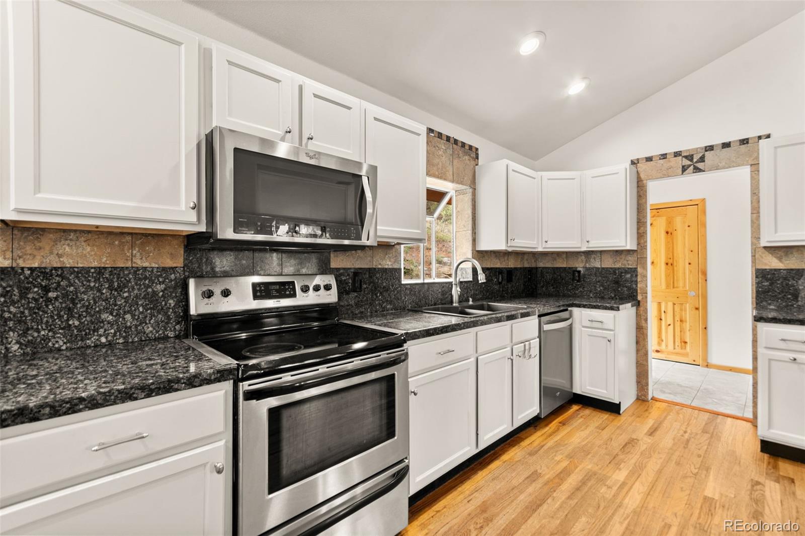 202 Badger Lane Bailey, CO 80421 - Photo 8 of 50 a kitchen with granite countertop a stove a sink and a microwave