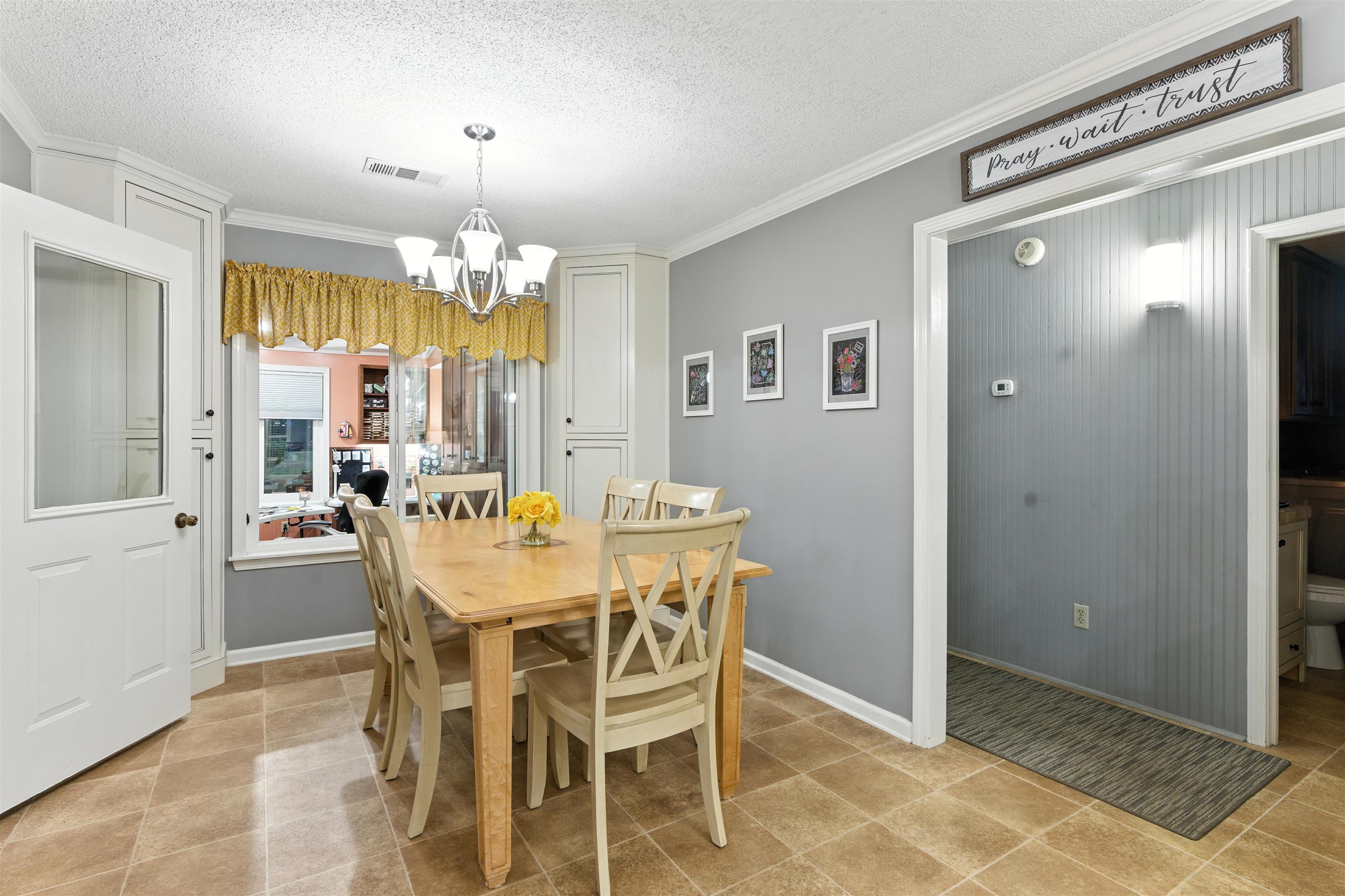8665 Brunswick Road Millington, TN 38053 - Photo 8 of 39 Dining room featuring a textured ceiling, ornamental molding, and a chandelier