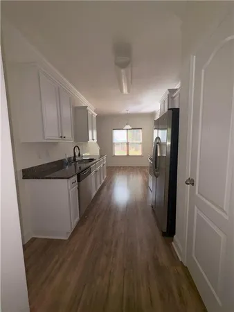 a kitchen with granite countertop a refrigerator a stove a sink and dishwasher with wooden floor