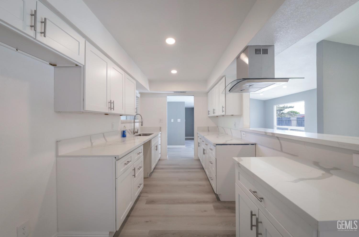 Undisclosed Address Bakersfield, CA 93306 - Photo 29 of 44 a large white kitchen with a sink and dishwasher a stove with wooden floors