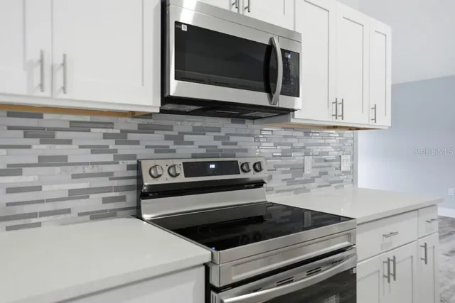 a kitchen with granite countertop white cabinets stainless steel appliances and a counter space