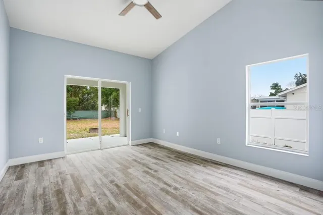 a view of an empty room with a window and wooden floor