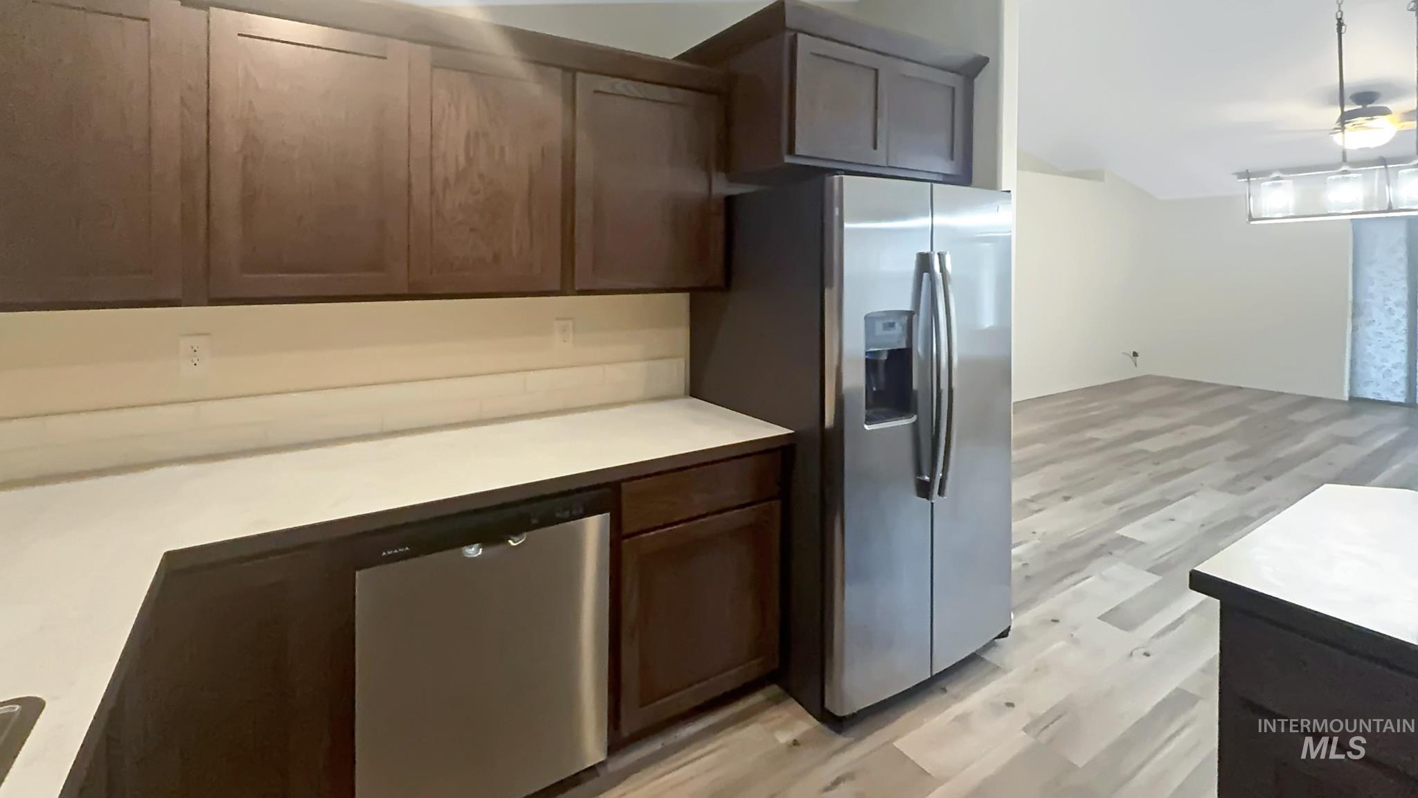 5223 Junegrass Way Caldwell, ID 83607 - Photo 13 of 16 Kitchen with light wood-type flooring, light countertops, stainless steel appliances, ceiling fan, and dark wood finish cabinetry