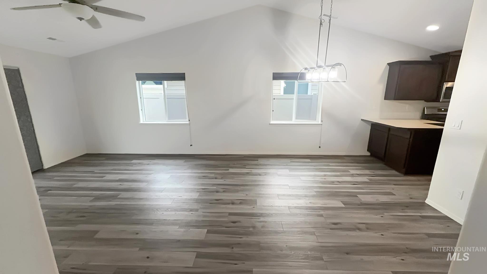 5223 Junegrass Way Caldwell, ID 83607 - Photo 3 of 16 Unfurnished dining area featuring lofted ceiling, dark wood-style flooring, suspended lighting, and a ceiling fan
