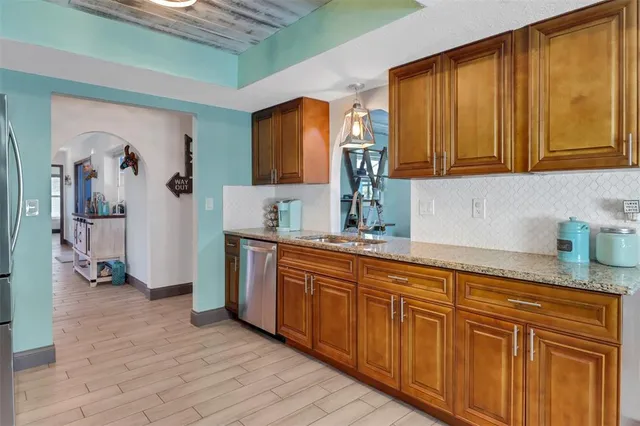 a kitchen with granite countertop wooden cabinets a sink and dishwasher