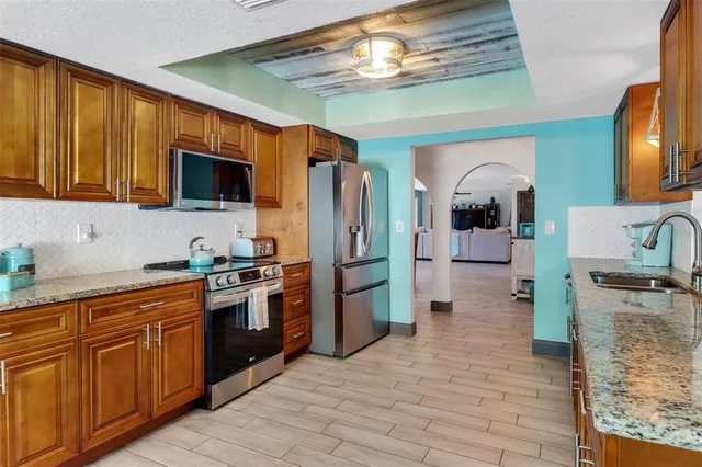 a kitchen with stainless steel appliances granite countertop a refrigerator a stove top oven a sink and dishwasher