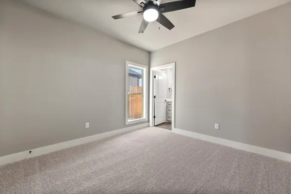 a view of an empty room and chandelier fan