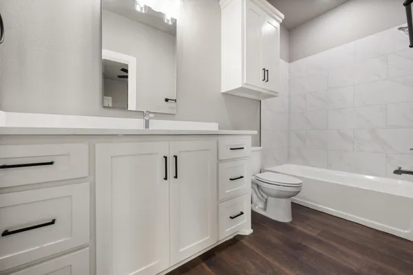a bathroom with a granite countertop toilet sink and mirror