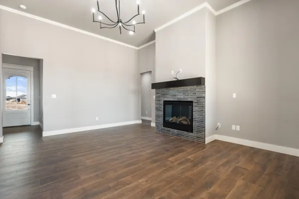 a view of an empty room with wooden floor fireplace and a window