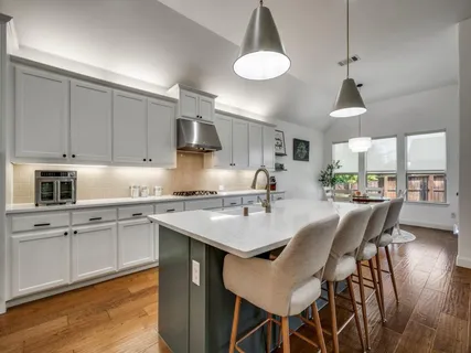 a kitchen with a dining table chairs sink and cabinets