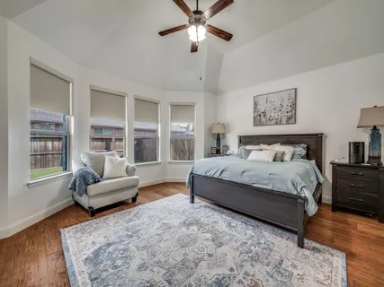 a spacious bedroom with a bed couch and windows