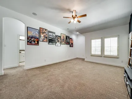 a view of an empty room with chandelier fan and windows