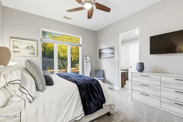 a spacious bedroom with a bed and a flat screen tv