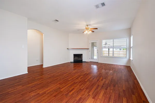 an empty room with wooden floor fireplace and windows