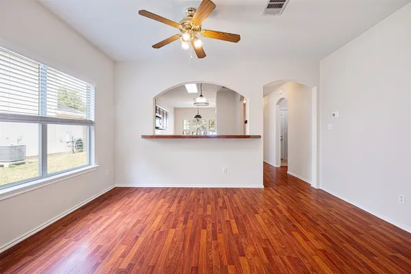 a view of a big room with wooden floor and a chandelier fan