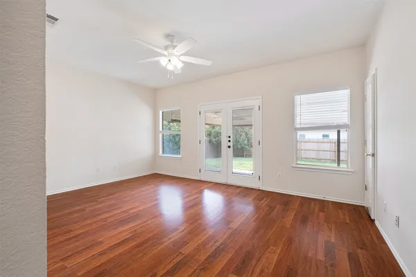 a view of an empty room with wooden floor and a window