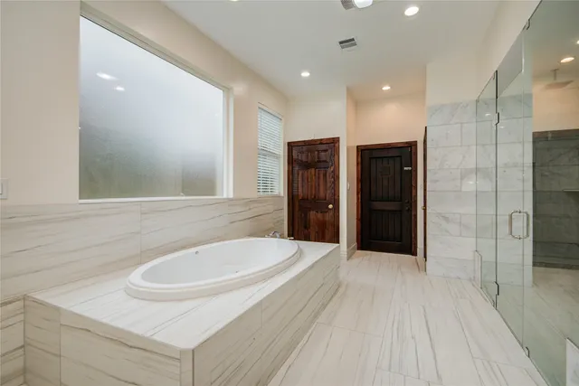 a bathroom with double vanity sink a two mirror a window and a bathtub