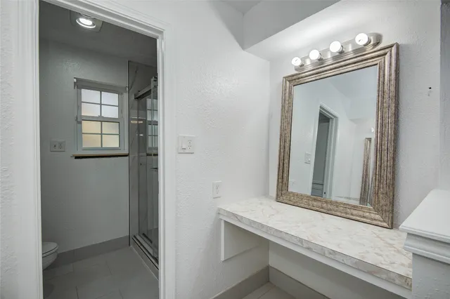 a bathroom with a granite countertop sink toilet and mirror