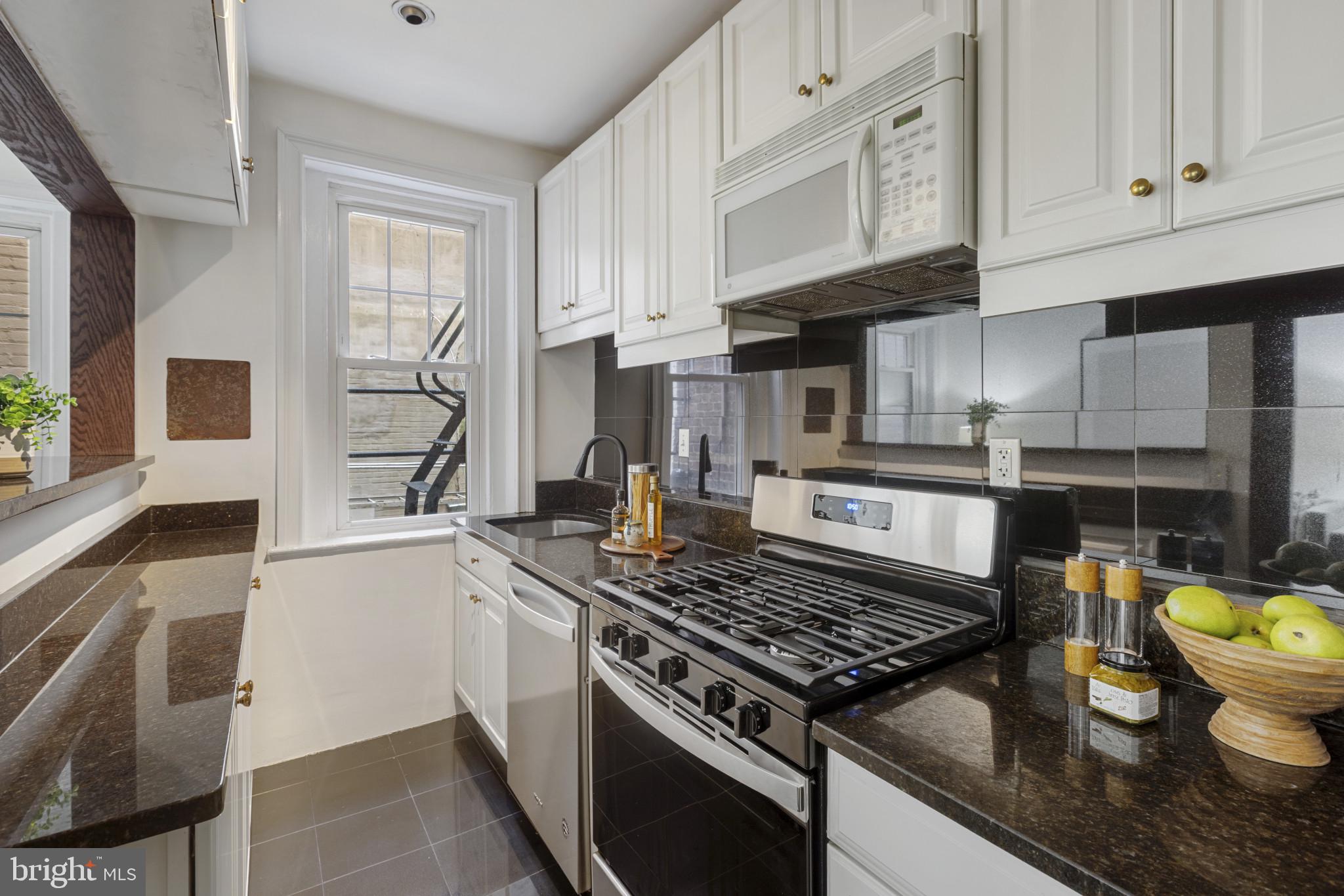 1332 15th Street Northwest, Unit 2 Washington, DC 20005 - Photo 10 of 28 a kitchen with stainless steel appliances granite countertop a stove a sink and a white cabinets