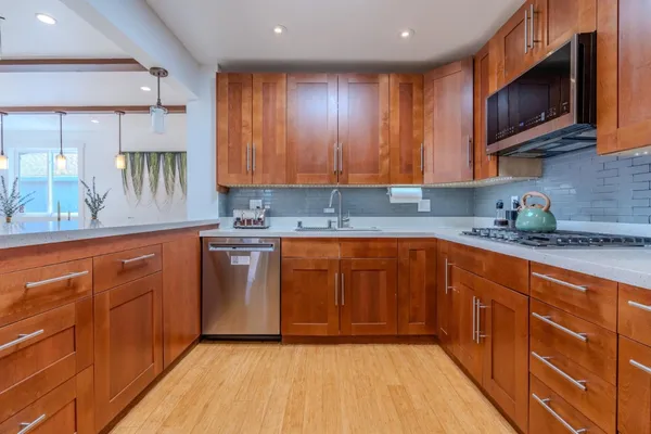 a kitchen with stainless steel appliances granite countertop wooden cabinets a stove top oven a sink and dishwasher