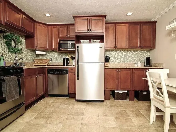 a kitchen with stainless steel appliances granite countertop a refrigerator stove top oven and sink