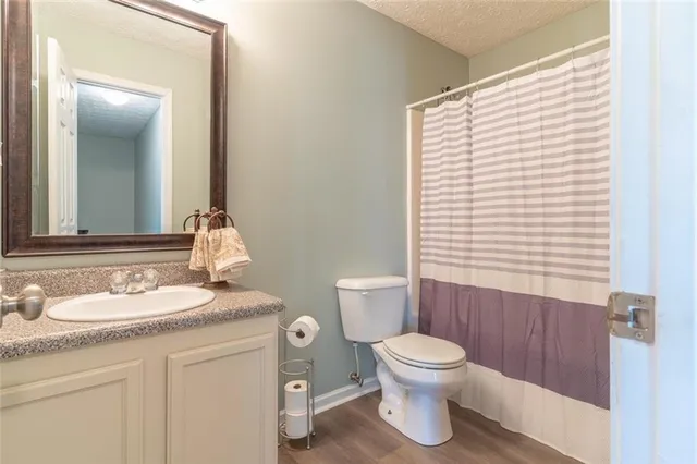 a bathroom with a granite countertop sink toilet a mirror and shower