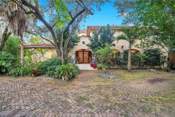 a backyard of a house with table and chairs under an umbrella
