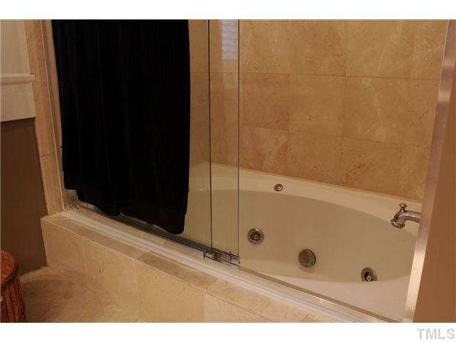 502 Cole Street Raleigh, NC 27605 - Photo 11 of 25 The whirlpool tub/shower has frameless glass doors and is complemented by the custom tile work.
