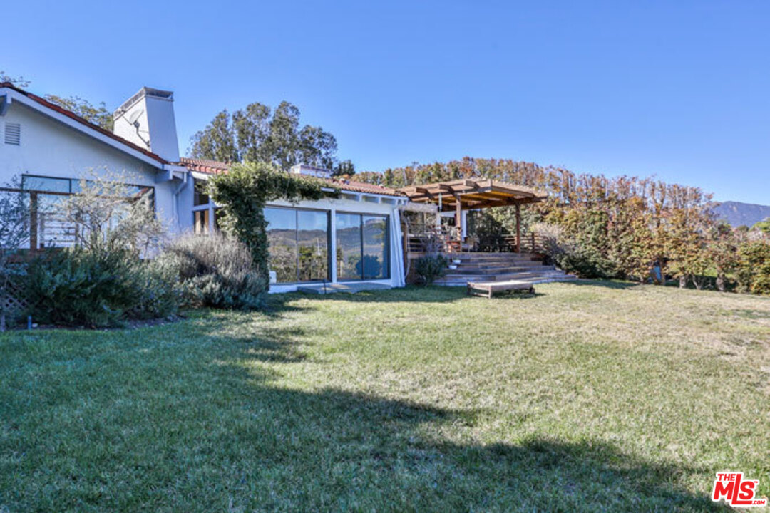 7050 Dume Drive Malibu, CA 90265 - Photo 12 of 13 a front view of a house with a garden and yard