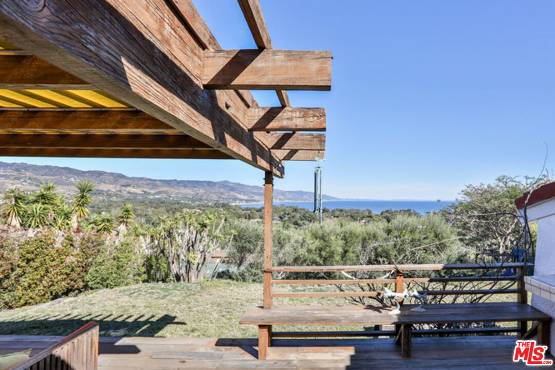 7050 Dume Drive Malibu, CA 90265 - Photo 9 of 13 a view of a patio with table and chairs with wooden floor and fence