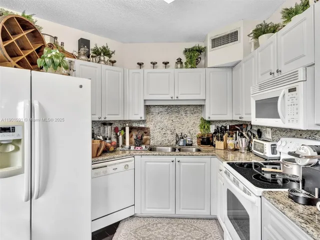 a kitchen with white cabinets and white appliances