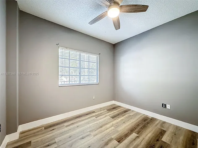 an empty room with a window and ceiling fan