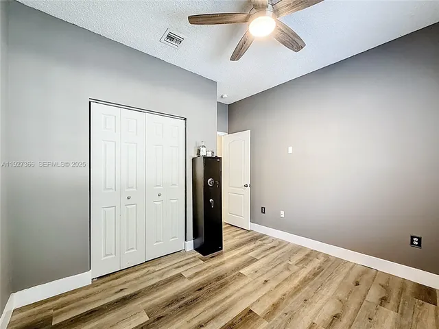 an empty room with closet and a ceiling fan