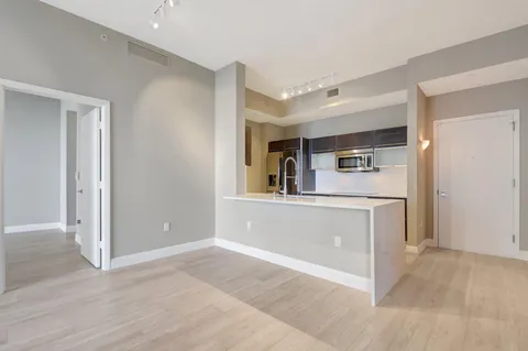 a view of an empty room with bookshelf and wooden floor