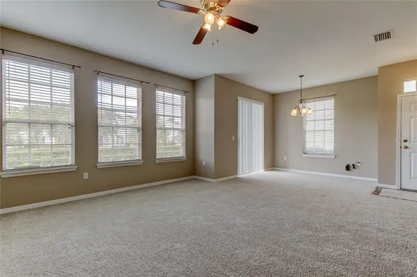 a view of an empty room with window and a kitchen