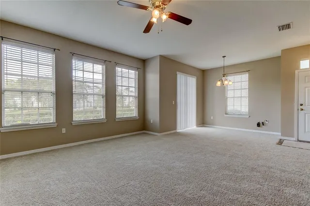 a view of an empty room with window and a kitchen