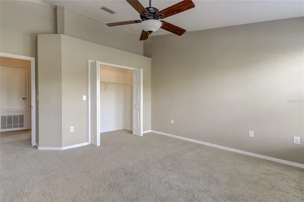 an empty room with closet and a ceiling fan