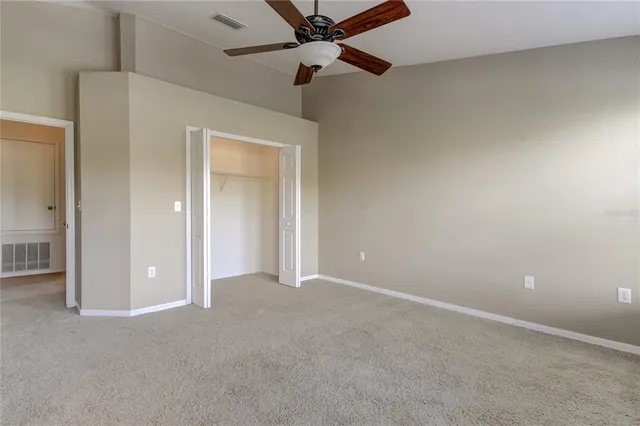 an empty room with closet and a ceiling fan