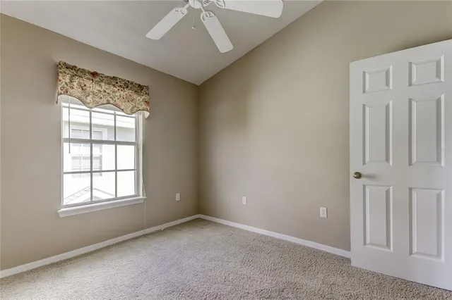 an empty room with a window and a fan