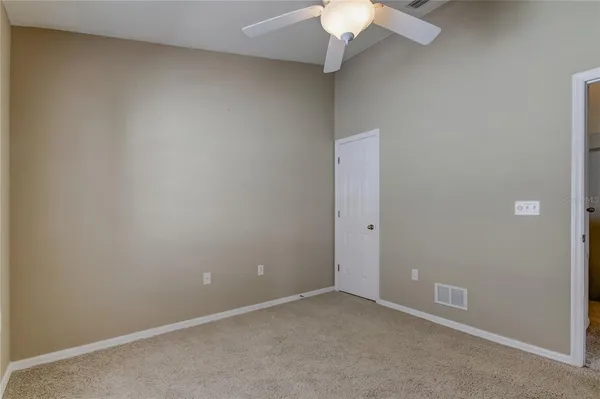 an empty room with a chandelier fan and closet area