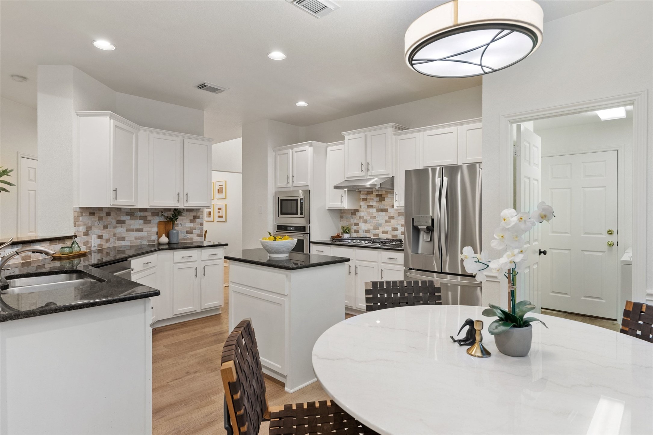 2950 Lantana Ridge Drive Austin, TX 78732 - Photo 7 of 40 a kitchen with stainless steel appliances kitchen island granite countertop a sink a stove a refrigerator and white cabinets with wooden floor